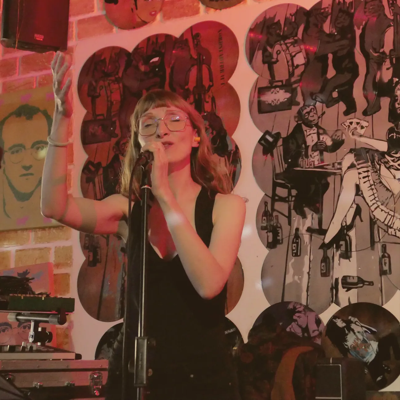 Sylvia singing with her arm raised in front of an illustrated wall