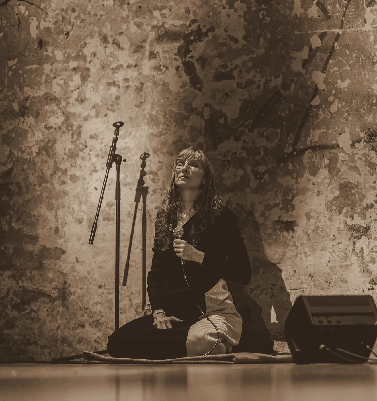 Sylvia kneeling on stage in front of a textured projected backdrop
