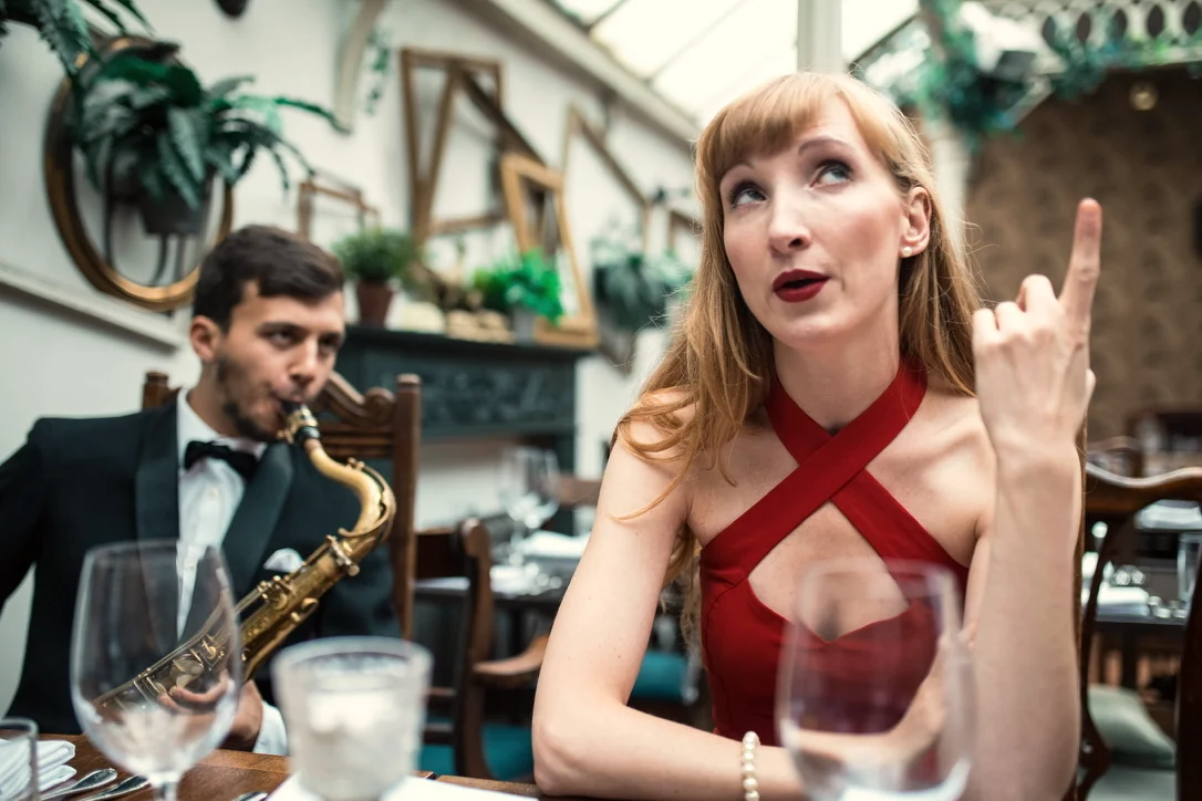 Sylvia in a red dress with a saxophonist at a dinner event