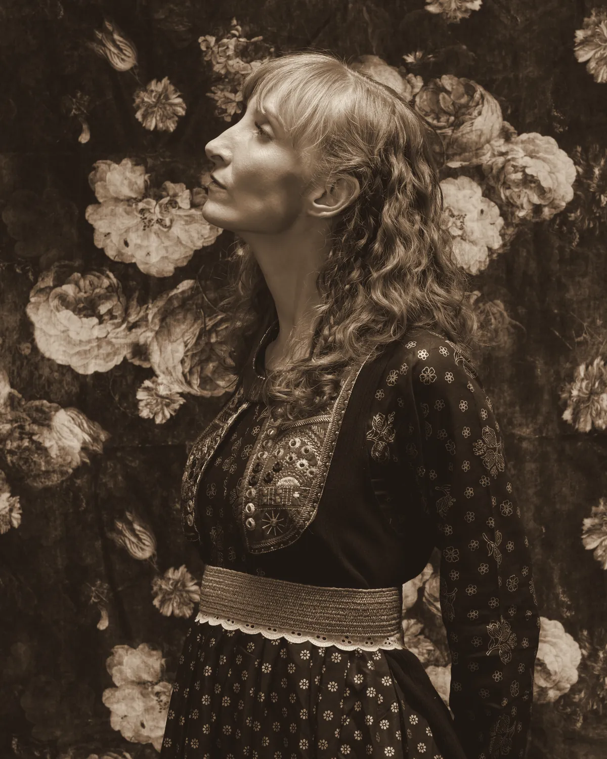Sylvia in profile in front of a floral backdrop