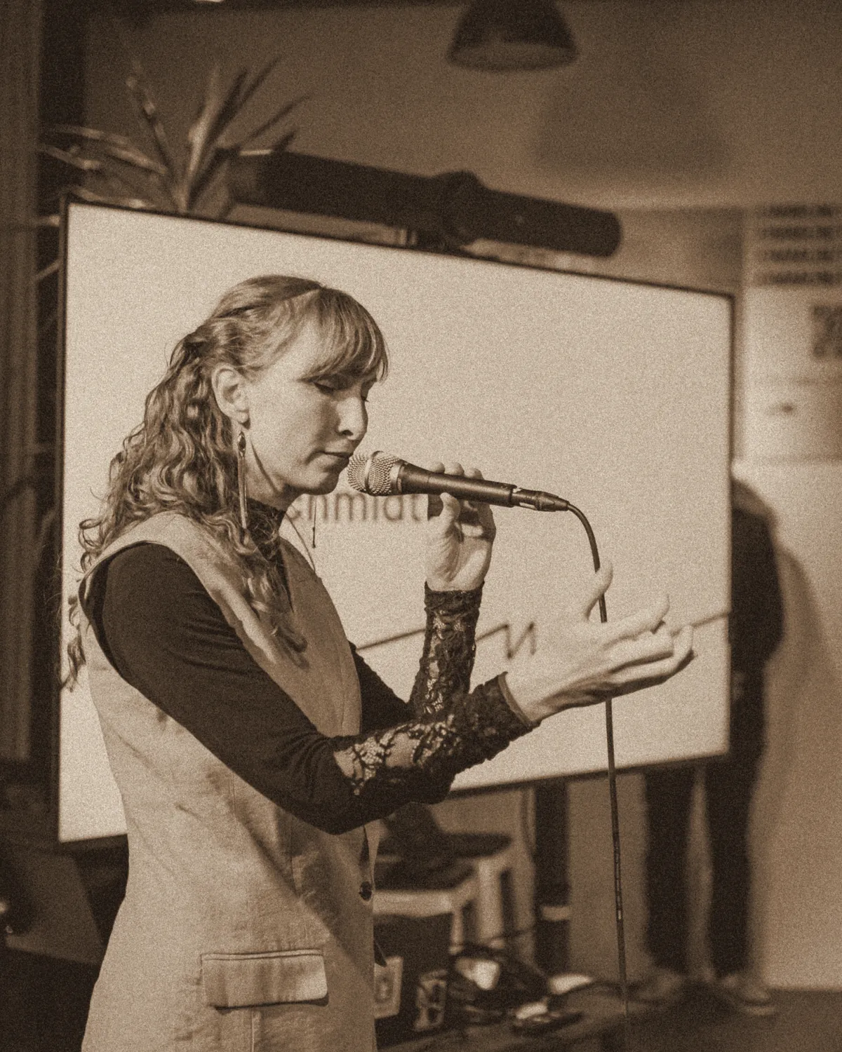 Sylvia singing at a microphone stand, gesturing with one hand